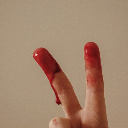 Finger mit Blut, die ein Peace-Zeichen formen