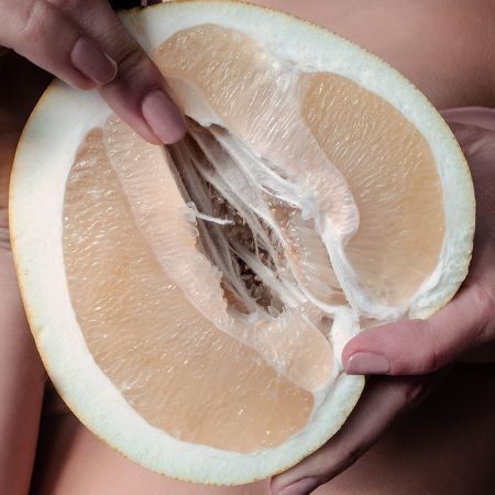 Frau hält eine geöffnete Pomelo